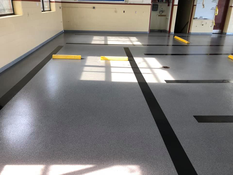 Industrial speckled grey epoxy floor with black lines and yellow parking blocks by Blendex Industrial Epoxy Floors in Lindenhurst, NY
