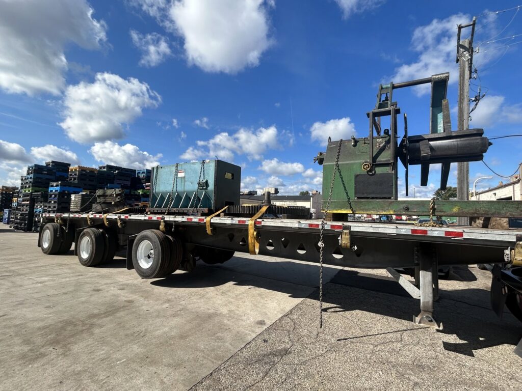Industrial equipment loaded onto a flatbed trailer for removal by Remove Recycle Remarket in Troy, MI.