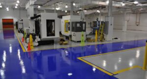An industrial facility with a blue and grey epoxy floor and yellow safety lines by Heavy Duty Floors, LLC in New Britain, CT.