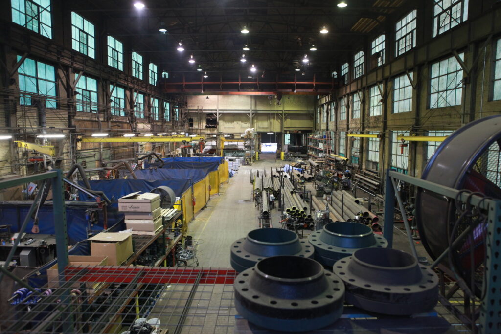 Interior of a large industrial facility or fabrication shop with pipes and equipment, representing work by McKamish, Inc. in Pittsburgh, PA