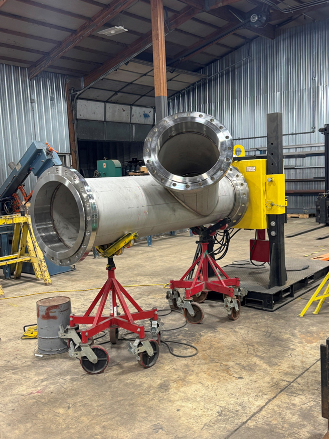 Large industrial pipes with flanges being assembled on stands inside a workshop by Jason Mechanical Corp in Joliet, IL.