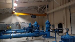 Workers performing an industrial pump room installation with large blue pipes and electrical panels for Valiant Electric Inc. in Kenosha, WI.
