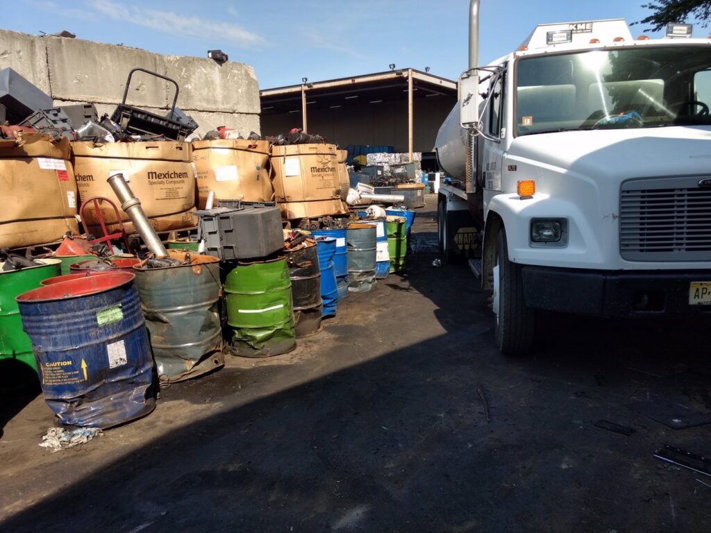 An industrial recycling yard with various materials and a truck at All American Alloys and Recycling Inc. in Elizabeth, NJ.