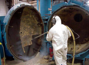A worker in a hazmat suit cleaning the interior of a large industrial vessel for Precision Industrial Maintenance, Inc. in Schenectady, NY.