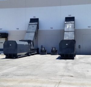Multiple industrial waste compactors and balers with conveyors outside a commercial building, installed by Premier Service in North Las Vegas, NV.