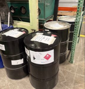 Black industrial drums with hazardous waste labels handled by Maine Labpack, Inc. in South Portland, ME
