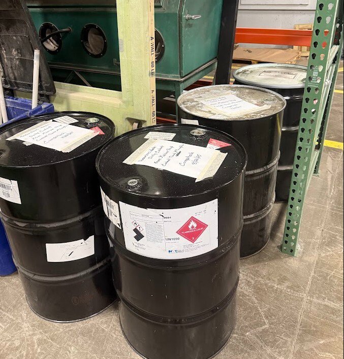 Black industrial drums with hazardous waste labels handled by Maine Labpack, Inc. in South Portland, ME
