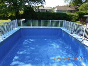 An inground pool with a new liner and white safety fence, showcasing installation by My Pool Guys of Erie, PA.