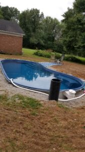 An inground pool shell installed in the ground with surrounding pipes and gravel, showing construction by My Pool Guys of Erie, PA.