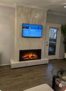 A newly installed fireplace and wall-mounted television in a living room by TS ELDER LLC in Phoenix, AZ