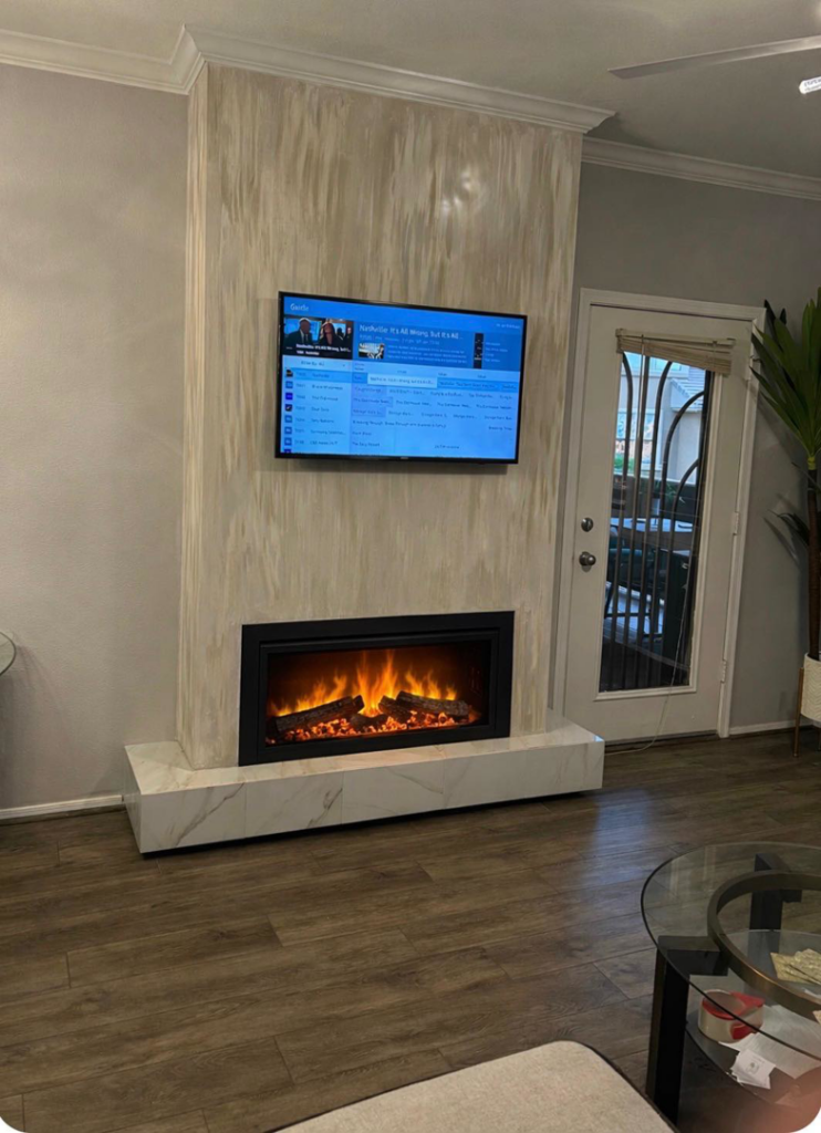 A newly installed fireplace and wall-mounted television in a living room by TS ELDER LLC in Phoenix, AZ