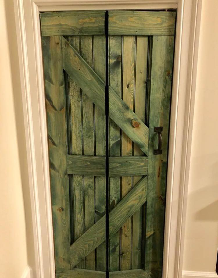 An installed custom green barn-style door by Two Girls Cleaning Services in Brunswick, ME.