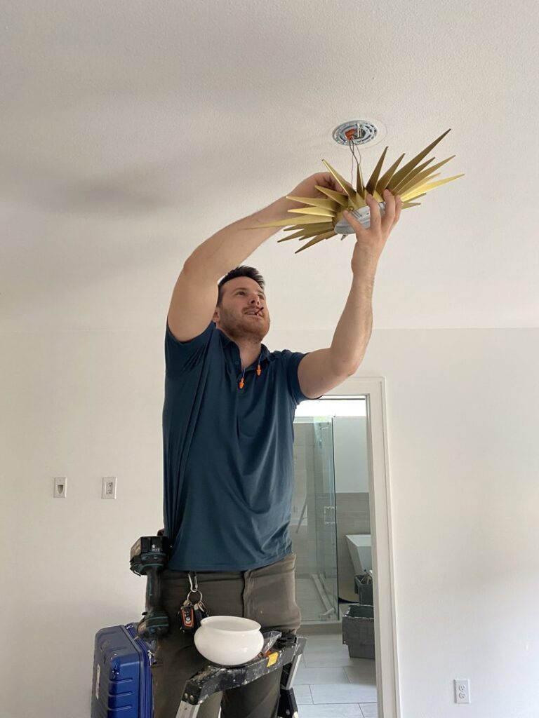 A skilled technician installing a modern ceiling light fixture as part of a remodel by Elite Handyman & Remodeling in Dallas, TX.