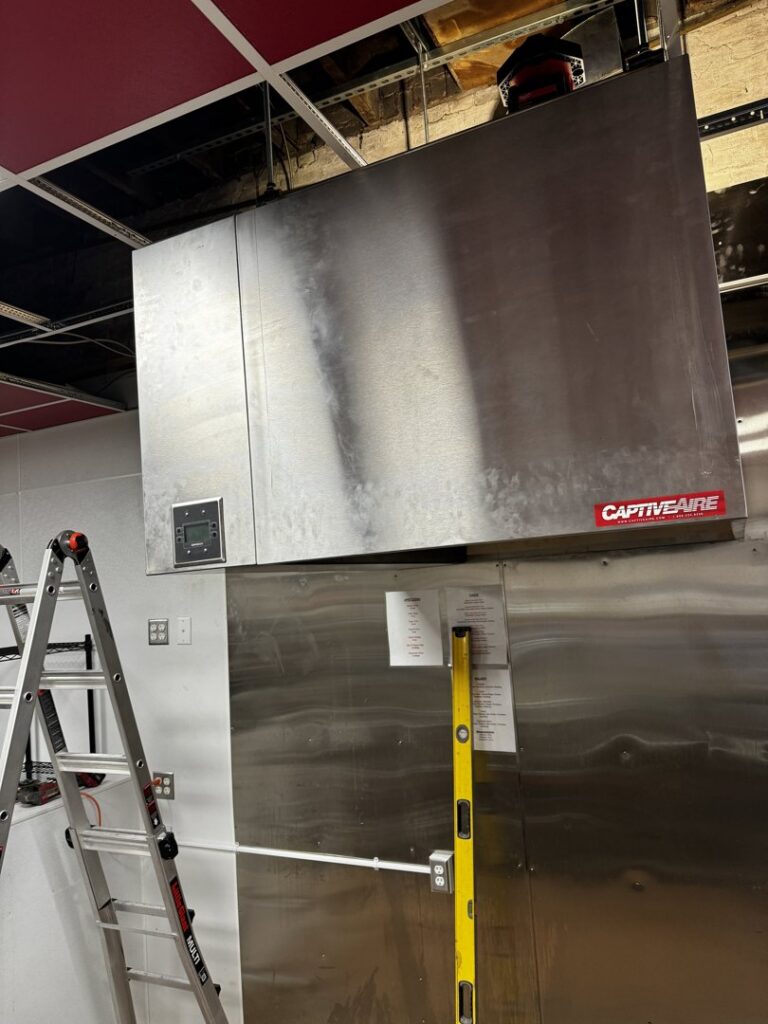 Handyman from ProKitchen Solutions installing a large commercial kitchen exhaust hood in Russiaville, IN