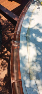 Close-up of a curved copper gutter section being installed with tools nearby by Charleston Exteriors in Charleston, SC.