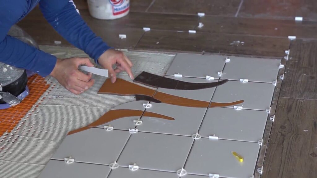 Close-up of hands installing decorative floor tiles, a service provided by JOMA Construction in Athens, GA.