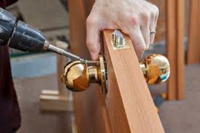 Close-up of hands installing a new door handle with a drill, a service by Pocatello Handyman in Pocatello, ID