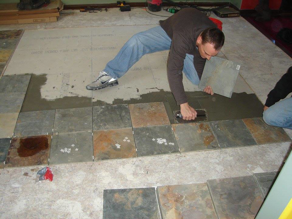 A handyman installing new floor tiles, a service offered by Honeycomb Handyman Services in Salt Lake City, UT.