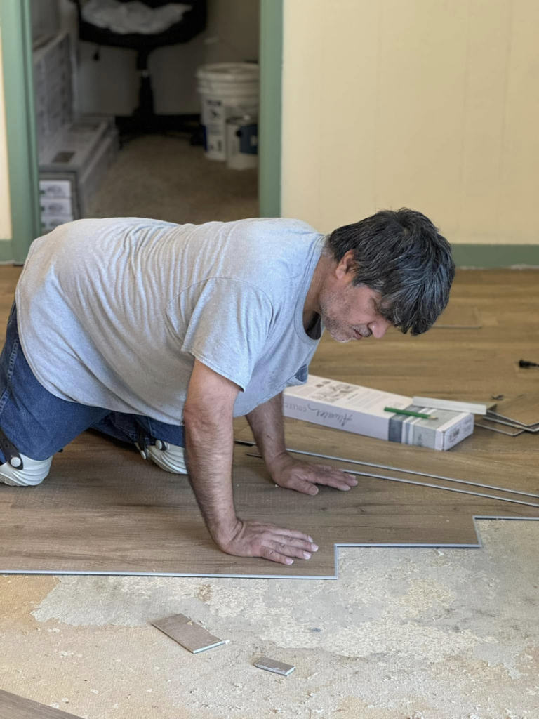 A handyman installing new laminate flooring planks in a room for Wheeler's Handyman Services in Vermillion, SD