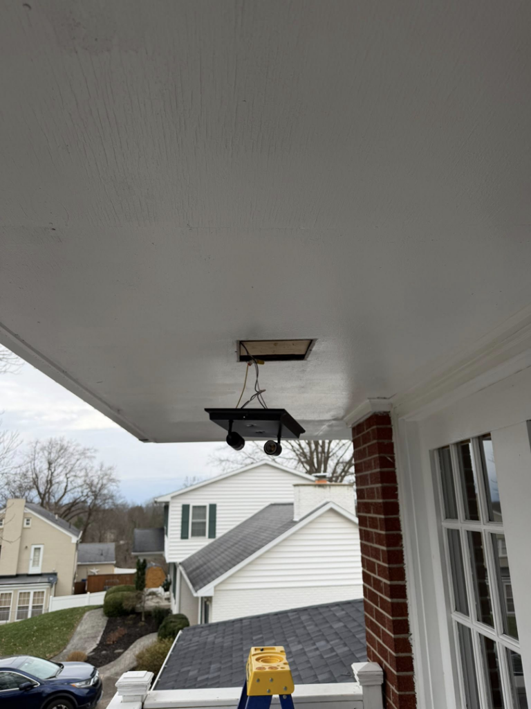 A handyman installing an outdoor porch light fixture, with a ladder visible, by HandyWorx Home Services LLC in Kenna, WV.