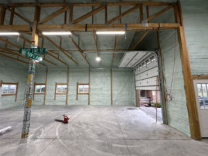 Wide view of a newly insulated building interior with an open garage door by Tumbarello Insulation in Peyton, CO.