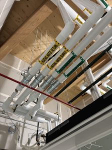 Insulated HVAC pipes and ductwork in a commercial ceiling by Performance Insulation of Wisconsin LLC in Green Bay, WI.