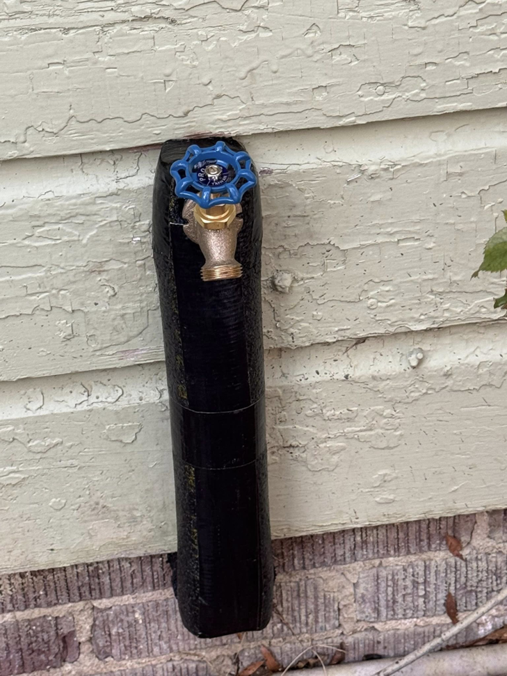 A newly insulated outdoor spigot with a blue handle on a house exterior, showcasing plumbing work by Helms Plumbing and Drains in Charlotte, NC.