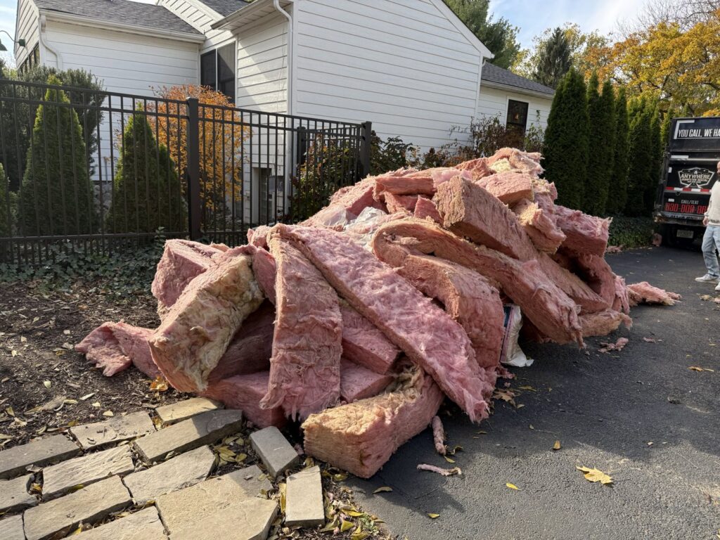 A large pile of pink insulation debris on a driveway, ready for removal by Anywhere Dumpster Rental in Bolingbrook Area, IL.