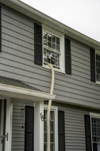 An insulation hose extending from a house window during a project by AB Insulation in Palmyra, NY.