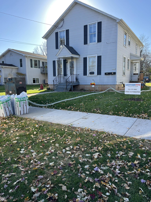 Insulation installation setup with equipment and bags outside a house by Weathertite Insulation in Oshkosh, WI.