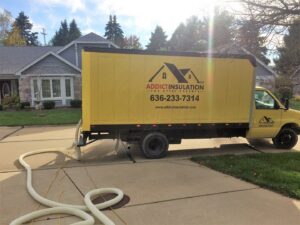An ADDICT INSULATION, LLC truck with an insulation hose at a residential job site in St. Charles, MO.