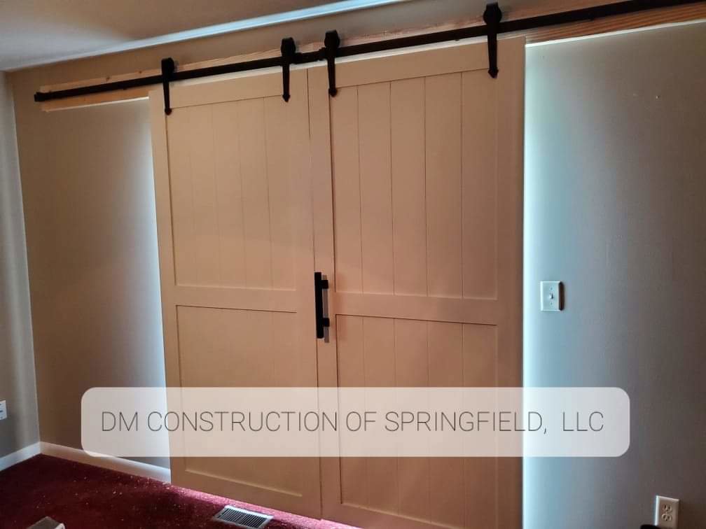 Newly installed white interior barn doors on a black track, by DM Construction of Springfield in Springfield, IL.