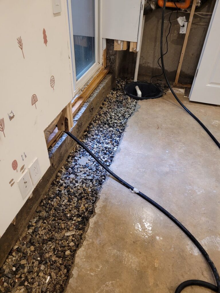 An interior basement drainage system with gravel, pipes, and a sump pump basin by Foundation Repair and Waterproofing in Philadelphia, PA.
