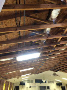 Interior view of a building under construction with exposed roof trusses and ductwork by Rampro Construction in Rock Hill, SC