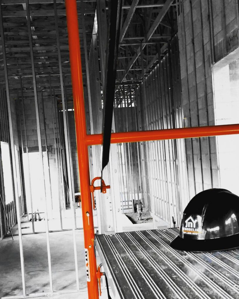 An interior construction site showing metal studs and scaffolding, indicating a general contractor project in progress by JNY Remodeling INC in Fort Lauderdale, FL.