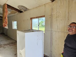 A person standing in a room with partially removed walls, indicating an interior demolition and cleanout job by T&G Dumping in Lorain, OH.
