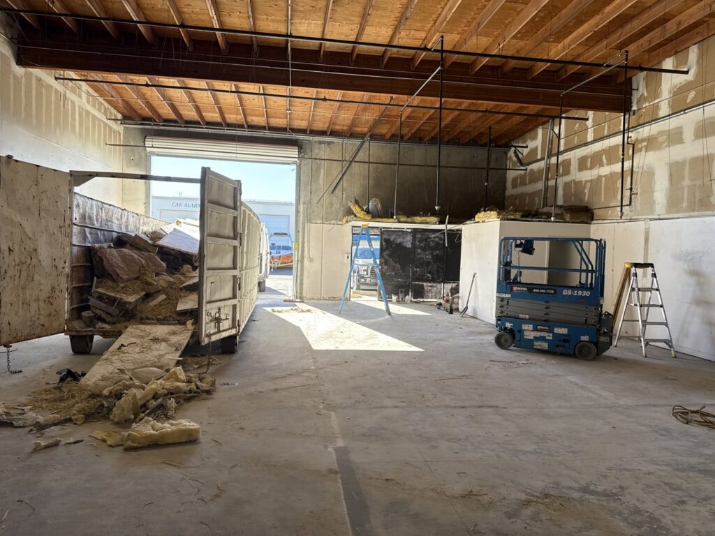 An interior space undergoing demolition with a dumpster collecting debris, handled by Waste Removal and Recycling in Sacramento, CA.