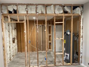 An interior room with exposed wooden studs and insulation, showing demolition and debris removal by HAVOC Demolition in Scottsdale, AZ.