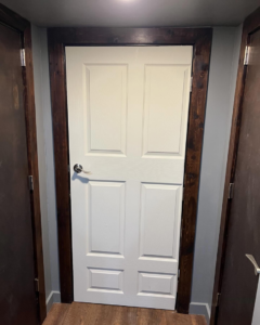 A newly installed white interior door with dark stained trim by Cord Construction in Winchester, KY