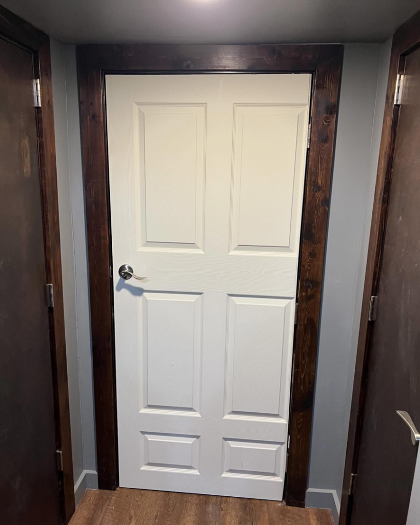 A newly installed white interior door with dark stained trim by Cord Construction in Winchester, KY