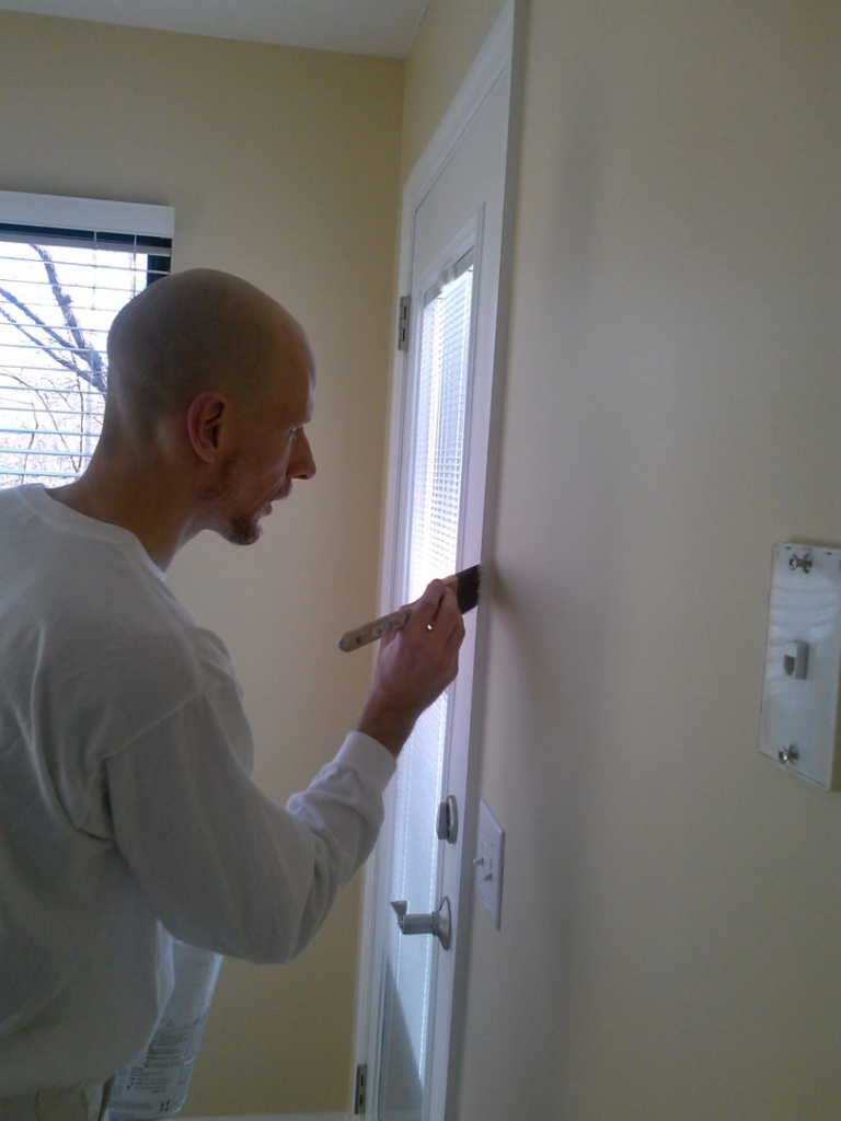 A professional painter carefully applying paint to interior door trim by Just Ducky Painting and Drywall Repair in Pegram, TN.