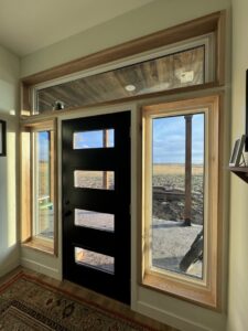 Interior view of a modern black door with new window and door trim installed by Northeast SD Handyman in Watertown, SD.