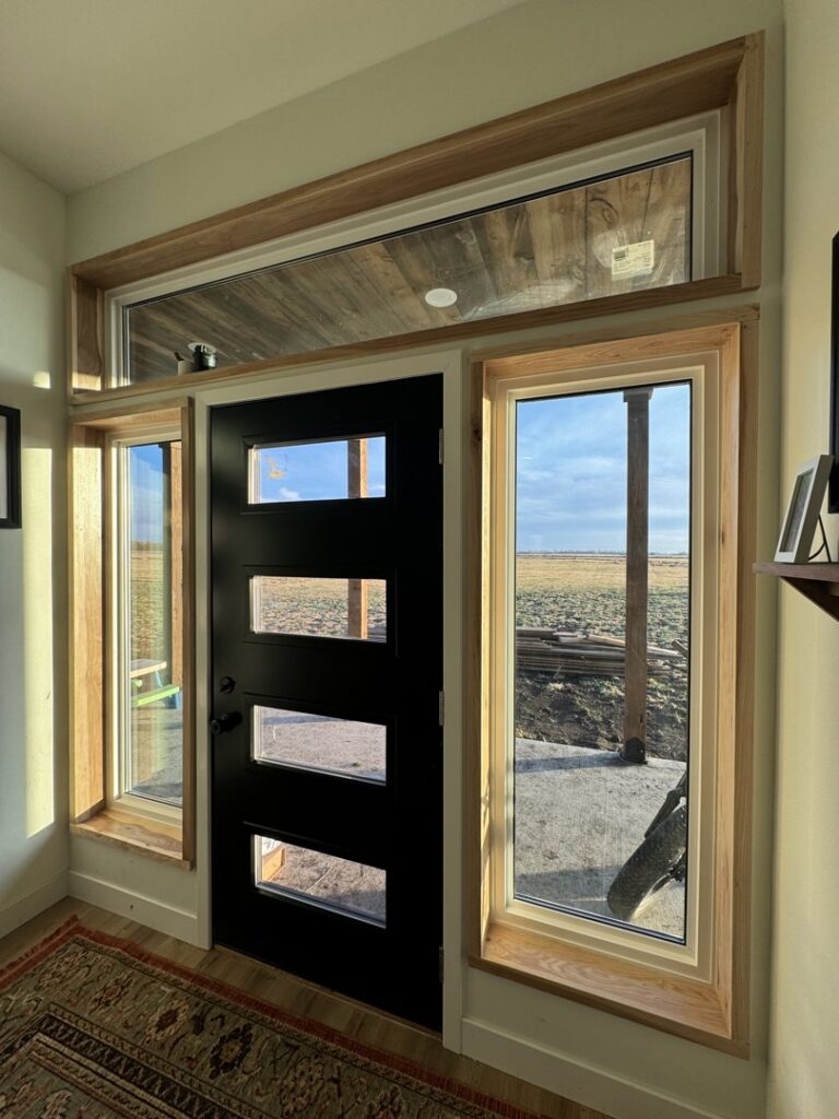 Interior view of a modern black door with new window and door trim installed by Northeast SD Handyman in Watertown, SD.