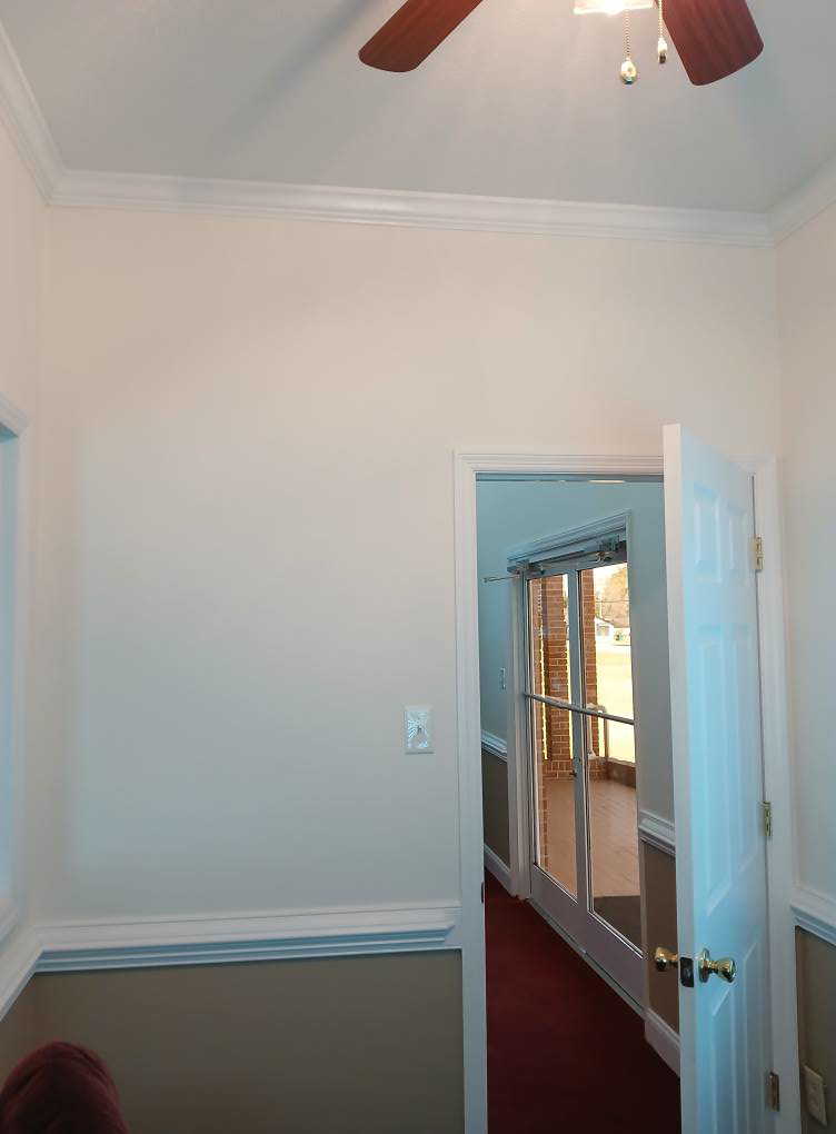 An interior doorway featuring detailed crown molding, baseboards, and a ceiling fan installed by Quiros Remodeling in Greenville, SC.