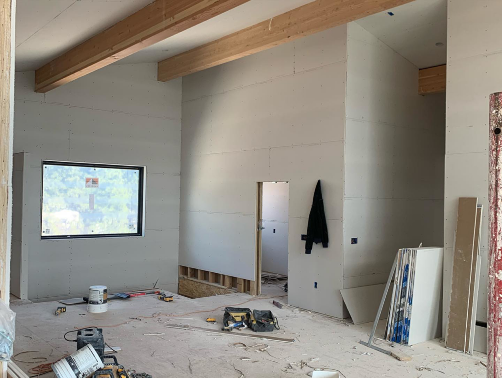 Interior room with newly installed drywall, exposed beams, and construction tools, showcasing Diamond Drywall services in Colorado Springs, CO.