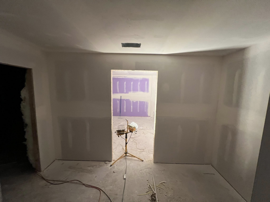 Interior drywall work in progress, illuminated by a work light, demonstrating handyman expertise by Brown & Son Contracting in O'Fallon, MO.
