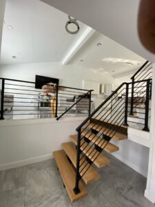 A modern interior featuring a floating wooden staircase with black metal railings, installed by Advanced Welding All in One Fabrication LLC in Guttenberg, NJ.
