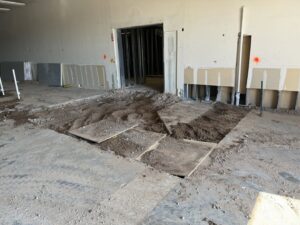 Interior commercial space with piles of dirt and debris from floor demolition, ready for junk removal by HAVOC Demolition in Scottsdale, AZ.
