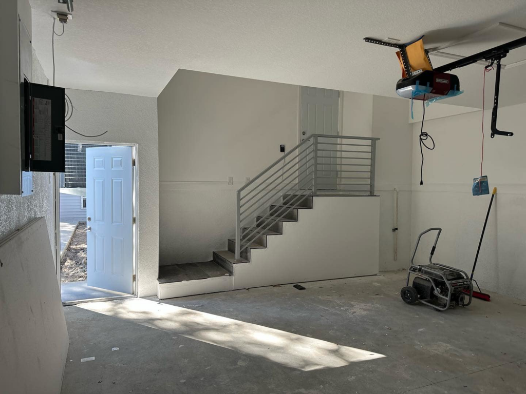 Interior of a garage under construction with new stairs and railings by Otero-Cossio Construction in Tampa, FL.