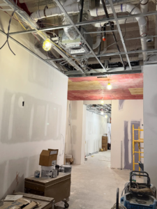 An interior hallway under construction with new drywall and ceiling work by On-Time Construction Services Inc. in Ashland, MA.